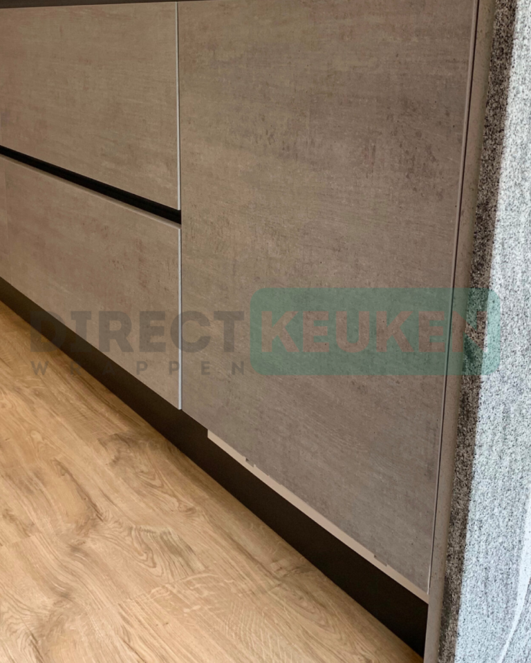 Detail van betonlook keukenfronten met donkere greeplijsten en plint