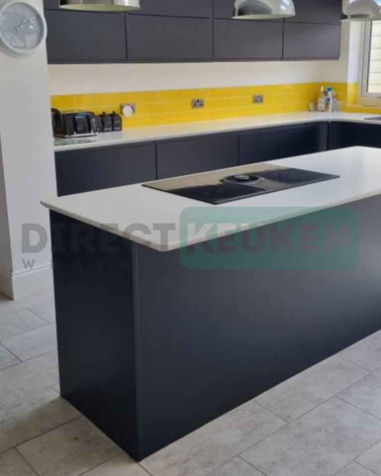 Donkere keuken met een kookeiland, wit werkblad en gele tegelachterwand